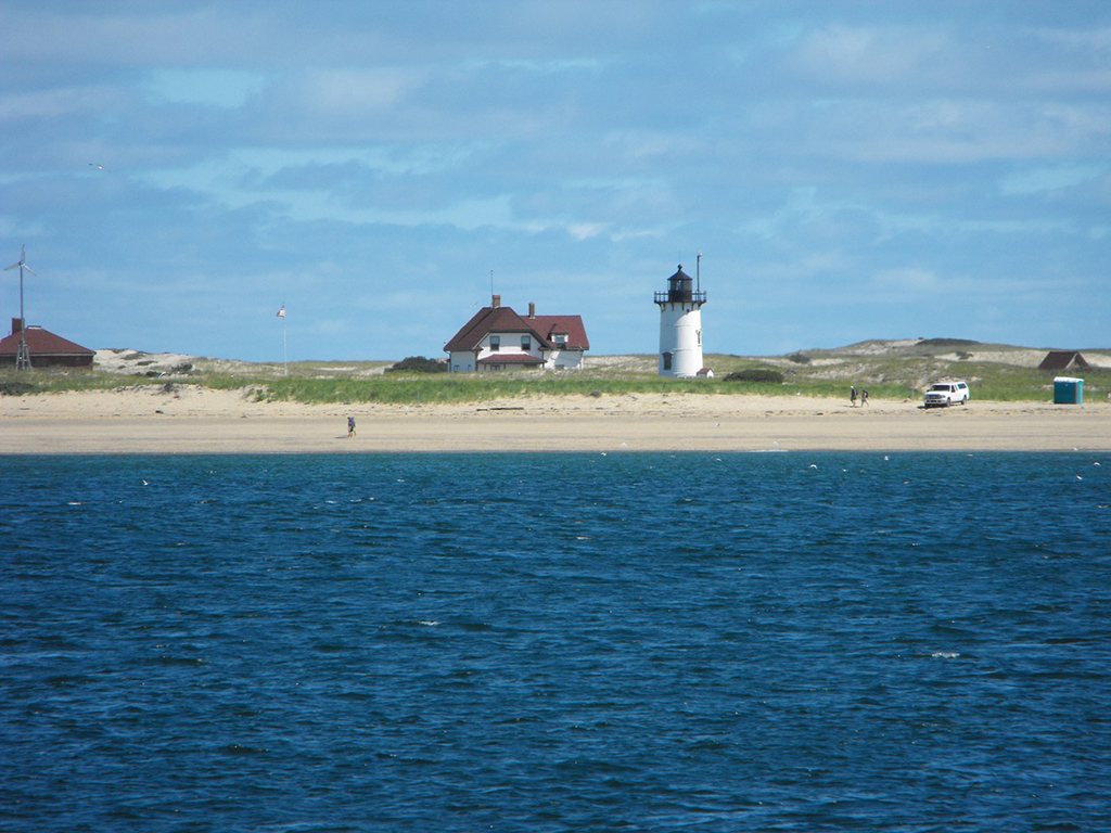 List of National Parks by State: A Complete List of All 400+ US National Parks 34 The blue ocean waves meet the sandy beach where a small building with a red roof and a white lighthouse with a black head are located
