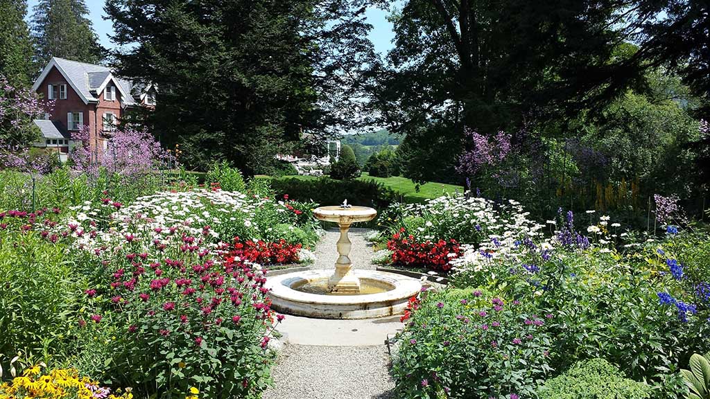 List of National Parks by State: A Complete List of All 400+ US National Parks 58 A fountain in the center of a garden surrounded by flowers and plants with a house in the top left corner