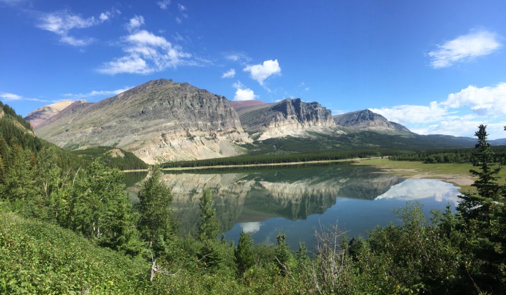 Cracker Lake Trail: One of the Most Beautiful Hikes in Glacier National Park 2 A still alpine lake reflecting the surrounding mountains and blue sky