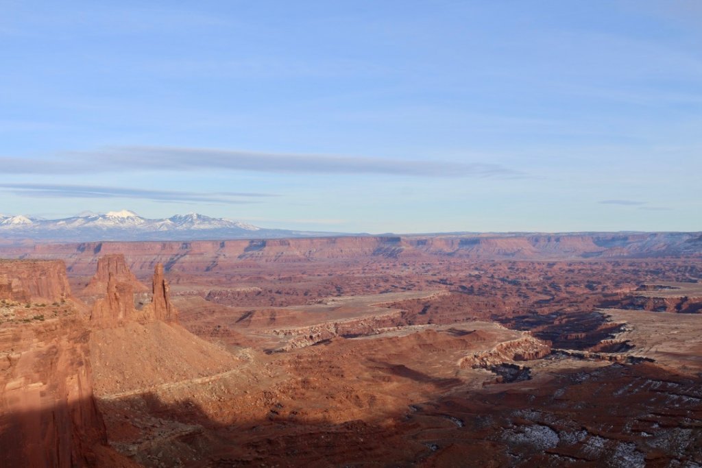 Visiting Canyonlands National Park: The Expert Travel Guide 5 An overlook of a red canyon with blue snow-capped mountains in the distant
