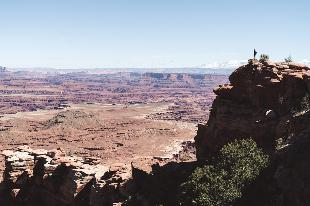 Visiting Canyonlands National Park: The Expert Travel Guide 17 A hiker on a rock cliff overlooking a canyon
