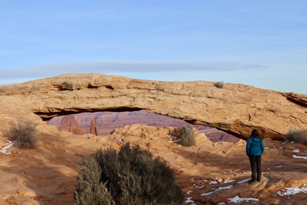 Visiting Canyonlands National Park: The Expert Travel Guide 10 A hiker stands admiring Mesa Arch when visiting Canyonlands National Park