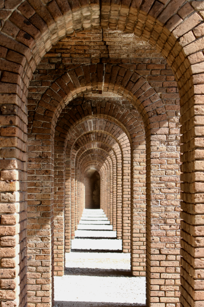 Camping at Dry Tortugas National Park: Everything You Need to Know 16 A brick hallway with many arches, seen while camping at Dry Tortugas National Park