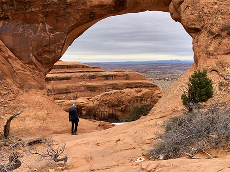 10 Best Hikes in Arches National Park That Lead to the Greatest Natural Arches in Utah 12 A woman stands in the middle of a circular arch. Partition Arch is one of the best hikes in Arches National Park