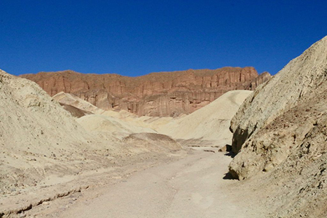 The 13 Best Hikes in Death Valley National Park You Won't Want to Miss 10 A trail through a narrow canyon with golden walls leads to a red towering wall. Golden Canyon is one of the best hikes in Death Valley.