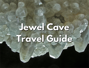 Jewel Cave National Monument 2 An image of a white crystal formations in a cave. Over the image, white text with a black shadow reads "Jewel Cave Travel Guide"