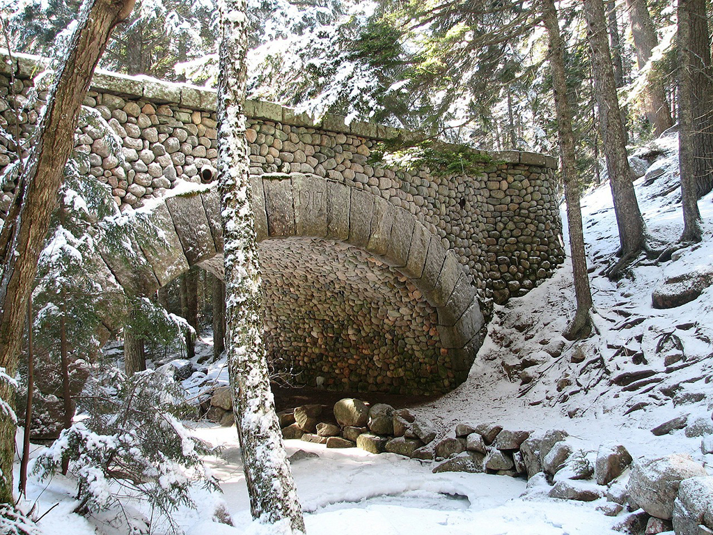 12 Things to Do in Acadia National Park That Will Take Your Breath Away 7 A picturesque stone bridge covered in snow. Walking, biking, or skiing the carriage roads is one of the best things to do in Acadia National Park.