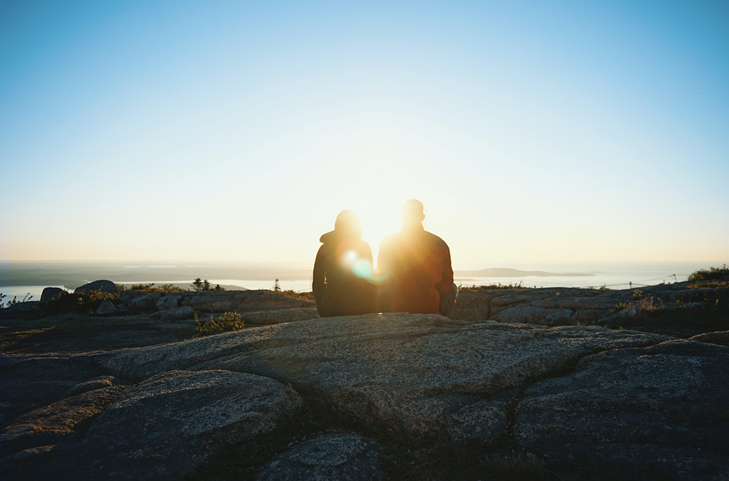 12 Things to Do in Acadia National Park That Will Take Your Breath Away 4 A couple sitting on a summit watches the sunrise. Watching the sunrise from Cadillac Mountain is one of the best things to do in Acadia National Park.