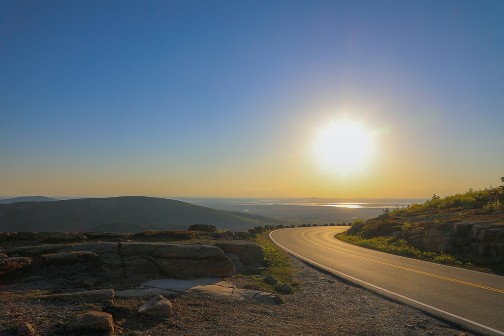 12 Things to Do in Acadia National Park That Will Take Your Breath Away 15 The sun rises over a paved road on a mountainside. Watching the sunrise or sunset is one of the best things to do in Acadia National Park.
