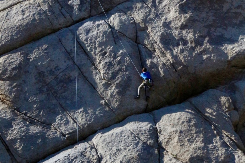 The 17 Most Amazing Things to Do in Joshua Tree National Park That Stole My Heart 15 A man scales the side of a large rock. Rock climbing is one of the best things to do in Joshua Tree.