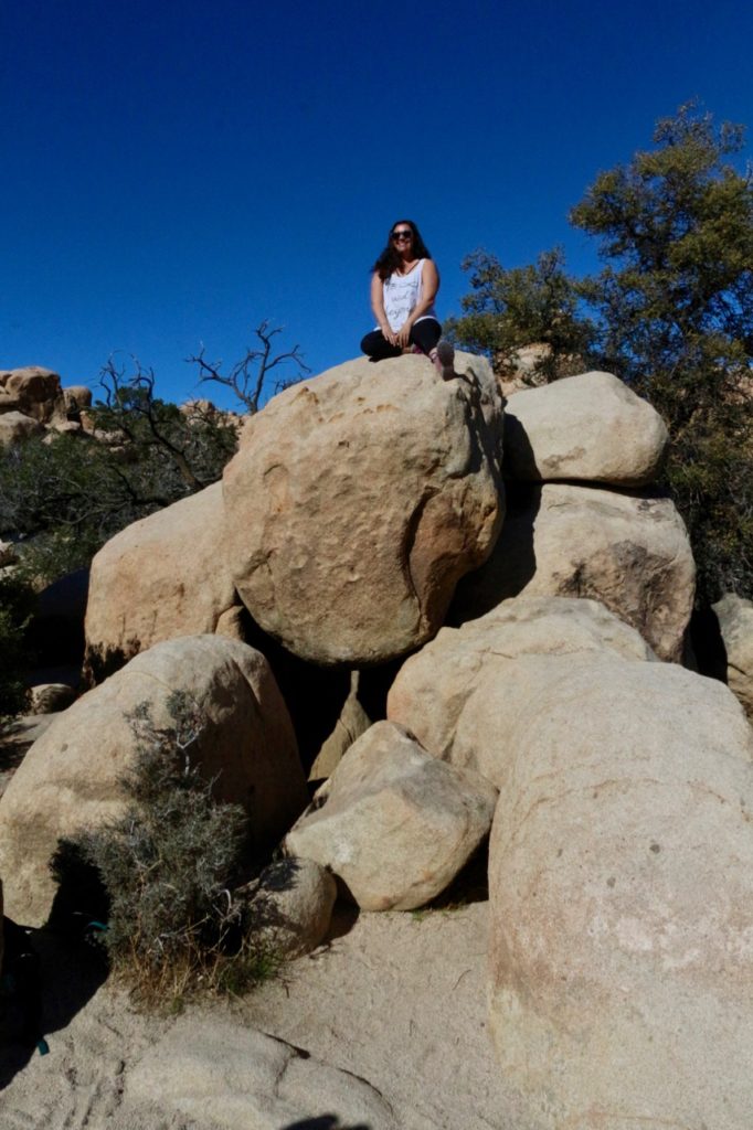 The 17 Most Amazing Things to Do in Joshua Tree National Park That Stole My Heart 16 A woman sitting on top of a pile of rocks. Rock climbing is one of the best things to do in Joshua Tree.
