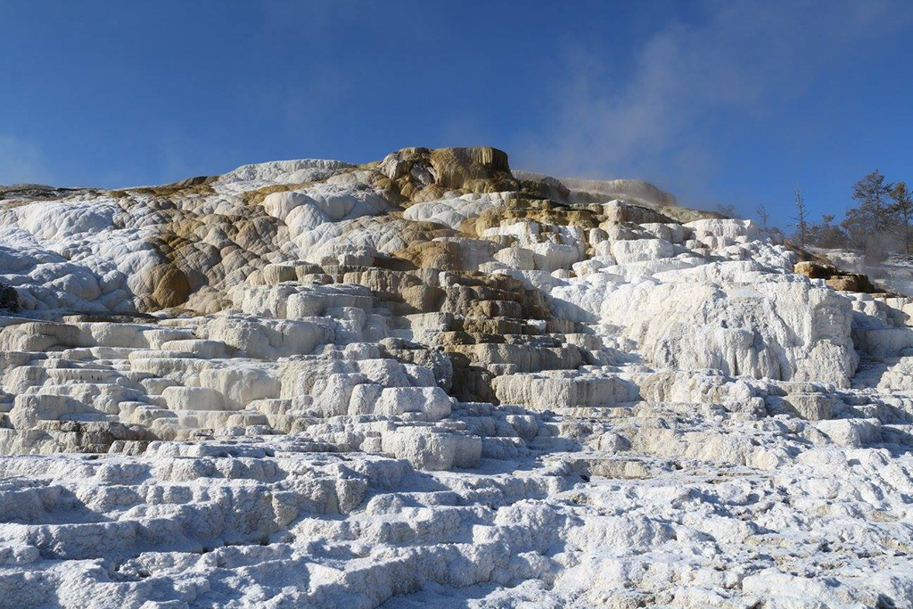 Yellowstone Itinerary: 4 Days in the World's First National Park 14 Steam comes off of a large limestone hot spring. Mammoth Hot Springs is one of the best attractions on this Yellowstone itinerary.