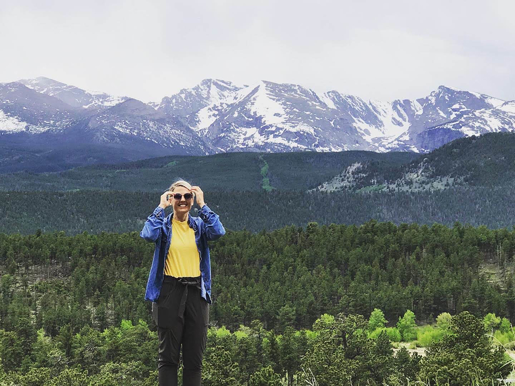 Driving Trail Ridge Road in Rocky Mountain National Park: Everywhere You Should Stop on The Exhilarating Drive 3 A woman smiles while taking in mountain views when driving Trail Ridge Road