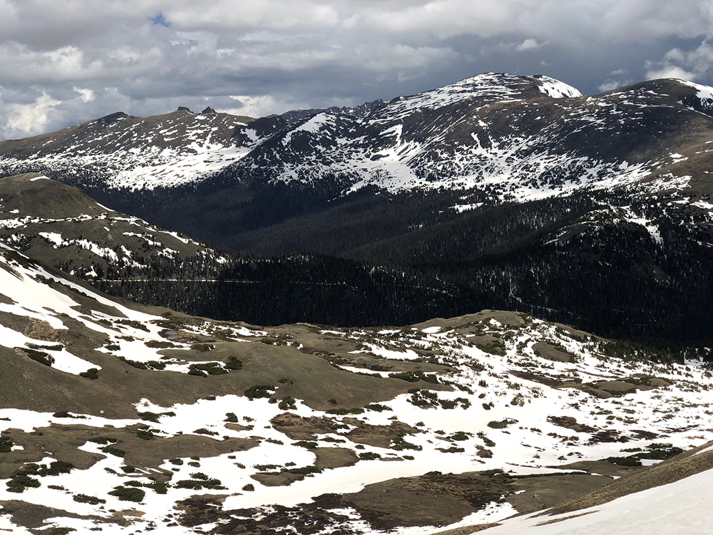 Driving Trail Ridge Road in Rocky Mountain National Park: Everywhere You Should Stop on The Exhilarating Drive 11 Patches of snow on green grass throughout the mountain range seen while driving Trail Ridge Road