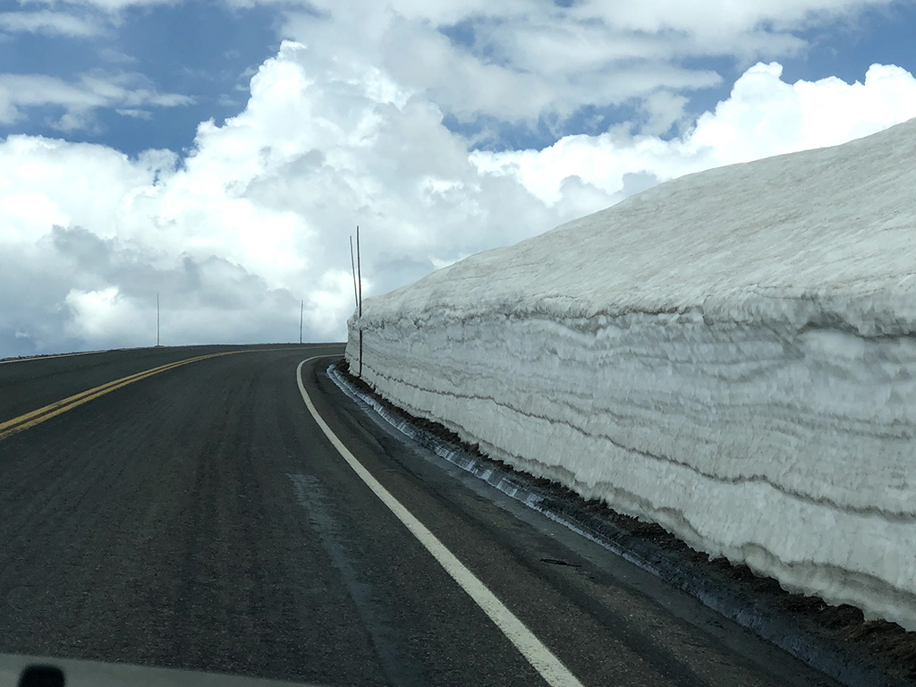 Driving Trail Ridge Road in Rocky Mountain National Park: Everywhere You Should Stop on The Exhilarating Drive 12 A large pile of snow on the side of a road after the pavement was plowed, seen while driving Trail Ridge Road