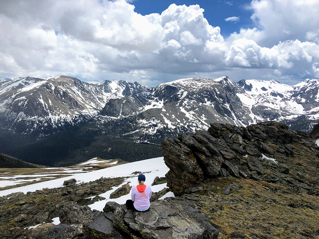 Driving Trail Ridge Road in Rocky Mountain National Park: Everywhere You Should Stop on The Exhilarating Drive 13 A woman sits on a rock taking in the view from driving Trail Ridge Road