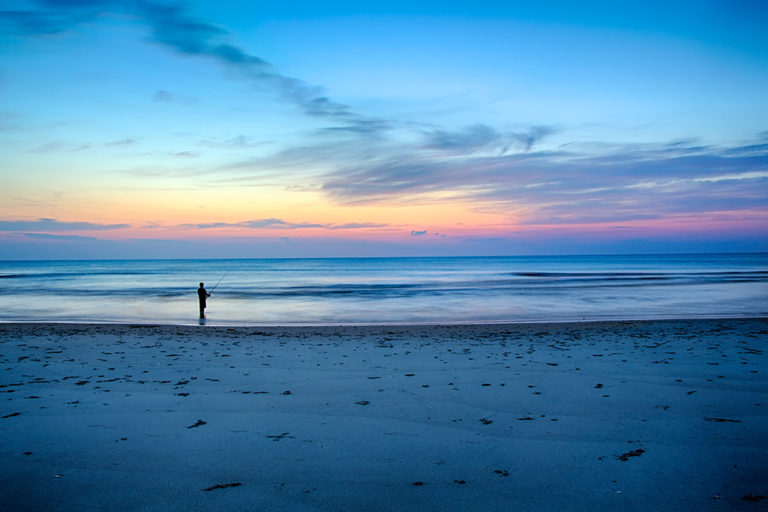 A fisherman on the beach of one of the national parks in North Carolina at sunset.