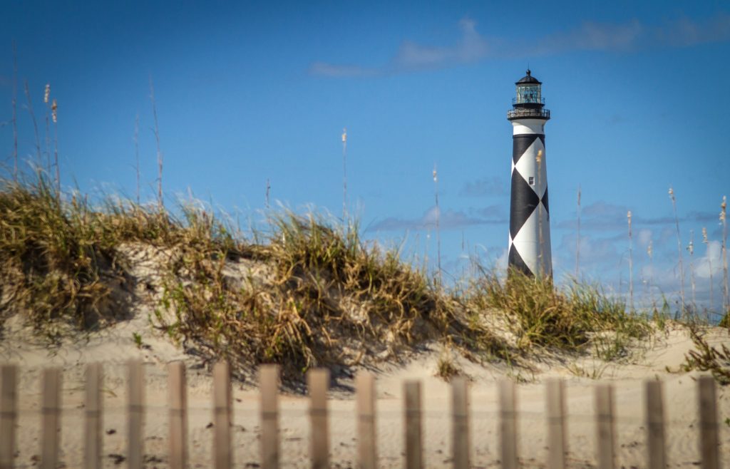 A black and white lighthouse on a sandy beach. Cape Lookout is one of the national parks in North Carolina.