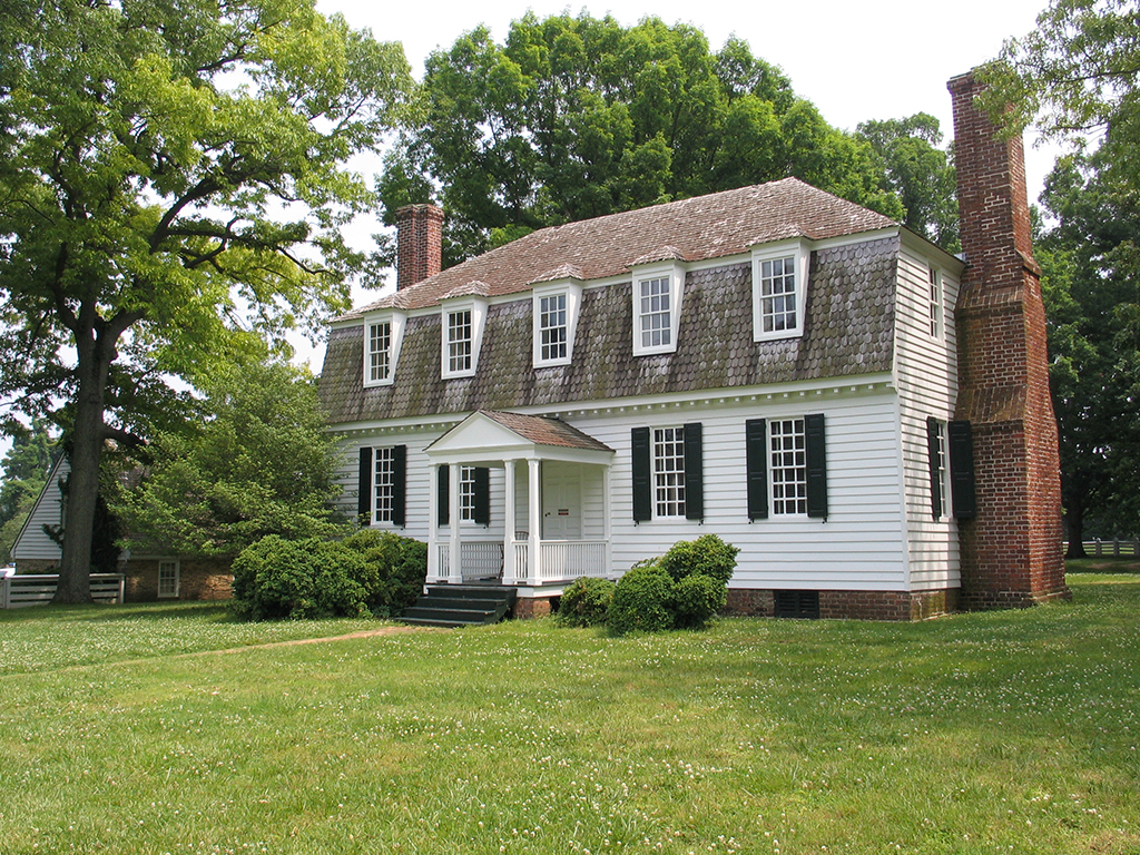 Follow the Footsteps of Alexander Hamilton in America's National Parks 6 A white house with a large red chimney on a green field