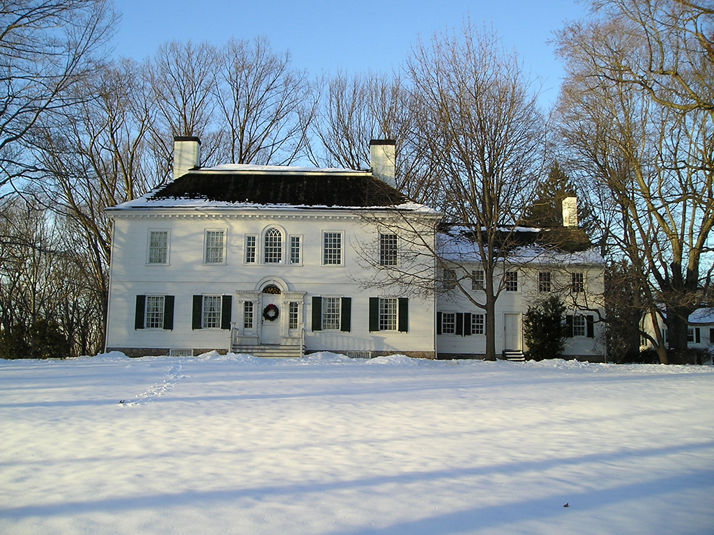 Follow the Footsteps of Alexander Hamilton in America's National Parks 5 A large white mansion with a snow-covered front lawn