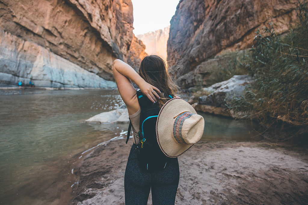 How to Spend 3 Days in Big Bend National Park: Itinerary 20 A woman reaches for her hat while standing on a beach along the Rio Grande in Big Bend's Santa Elena Canyon