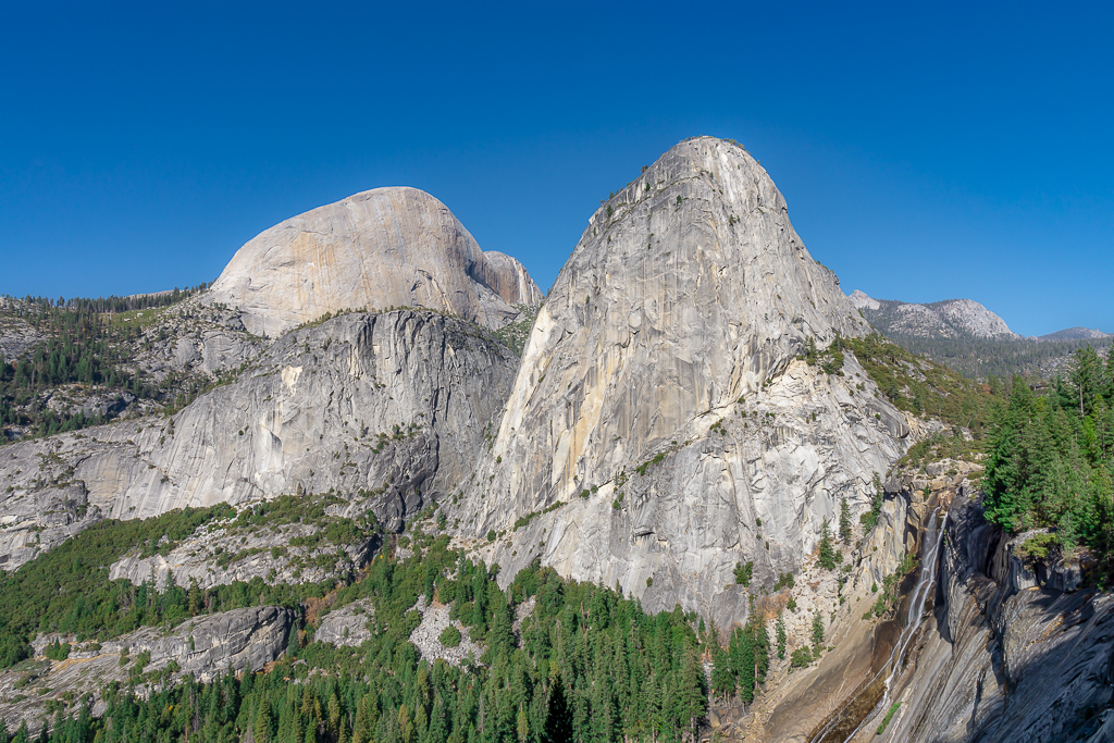 8 of the Best Hikes in Yosemite National Park for Breathtaking Views 26 A waterfall cascades toward the ground between two granite monoliths along Mist Trail, one of the best hikes in Yosemite National Park