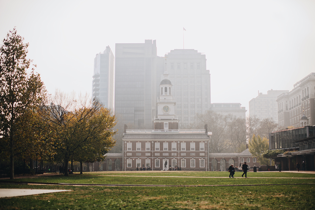 List of US National Parks in Alphabetical Order (All 400+!) 26 A historic brick building in the background with green grass in the foreground. Modern skyscrapers stand behind the brick building.