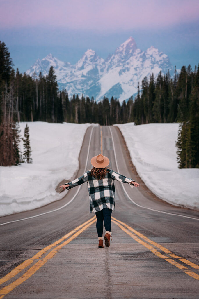 List of National Parks by State: A Complete List of All 400+ US National Parks 13 A woman walks down an empty paved road with her arms outstretched