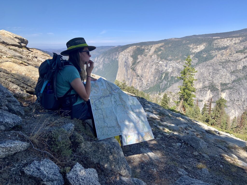 Let Us Plan Your Personalized National Park Trip 1 A woman reviews a map while looking at the landscape before her