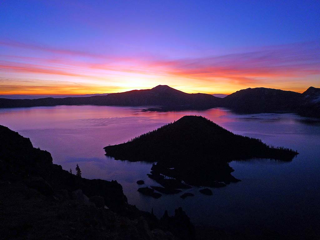 5 Incredible National Parks in Oregon 1 The sunset creates beautiful orange and purple hues over Crater Lake, one of the national parks in Oregon