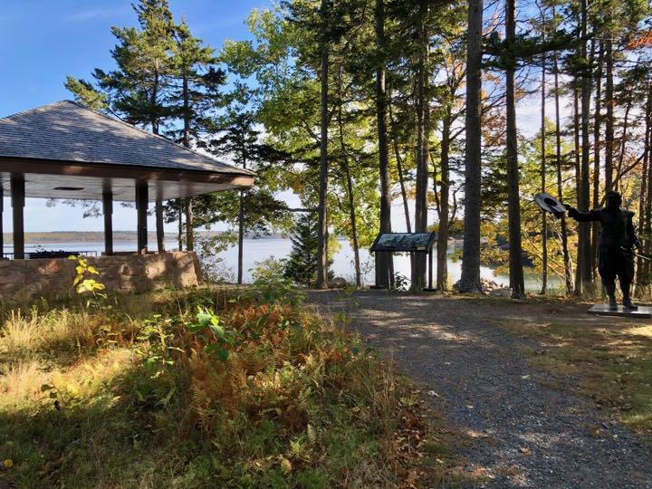 4 Phenomenal National Parks in Maine 37 A gravel path leads to a pavilion overlooking a river near an informative sign and a bronze statue