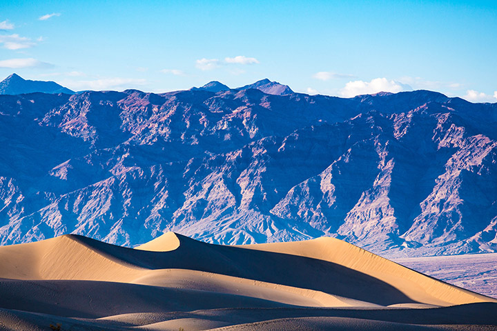 2 Day Death Valley Itinerary: How to See the Best of the West in 2 Days 49 Sand dunes below towering blue mountains in Death Valley