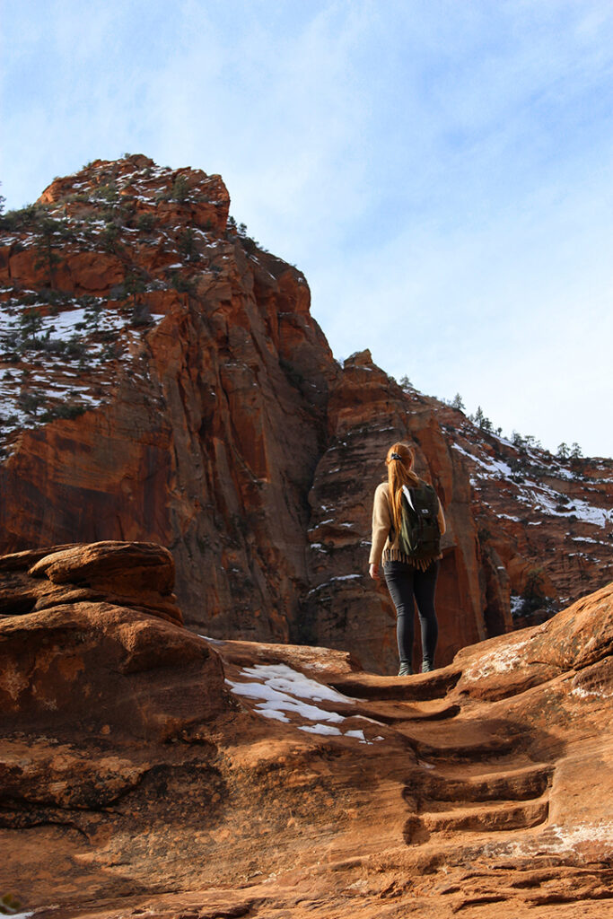 One Day in Zion: 4 Ways to Spend an Epic 24 Hours in Zion National Park 36 A female hiker climbs a trail to red rocks while spending one day in Zion