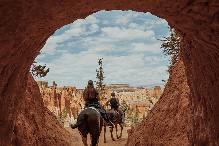 20 Fun Things to Do in Bryce Canyon National Park 12 Two people ride horses through a natural bridge, one of the best things to do in Bryce Canyon