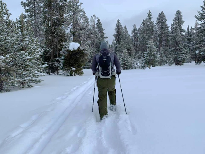 Yellowstone in Winter: Everything You Need to Know for A Spectacular Trip 9 A hiker snowshoes across snow toward trees
