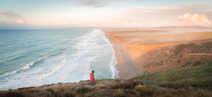 20 Incredible Things to Do in Point Reyes National Seashore 32 A hiker in red walks above a sandy beach