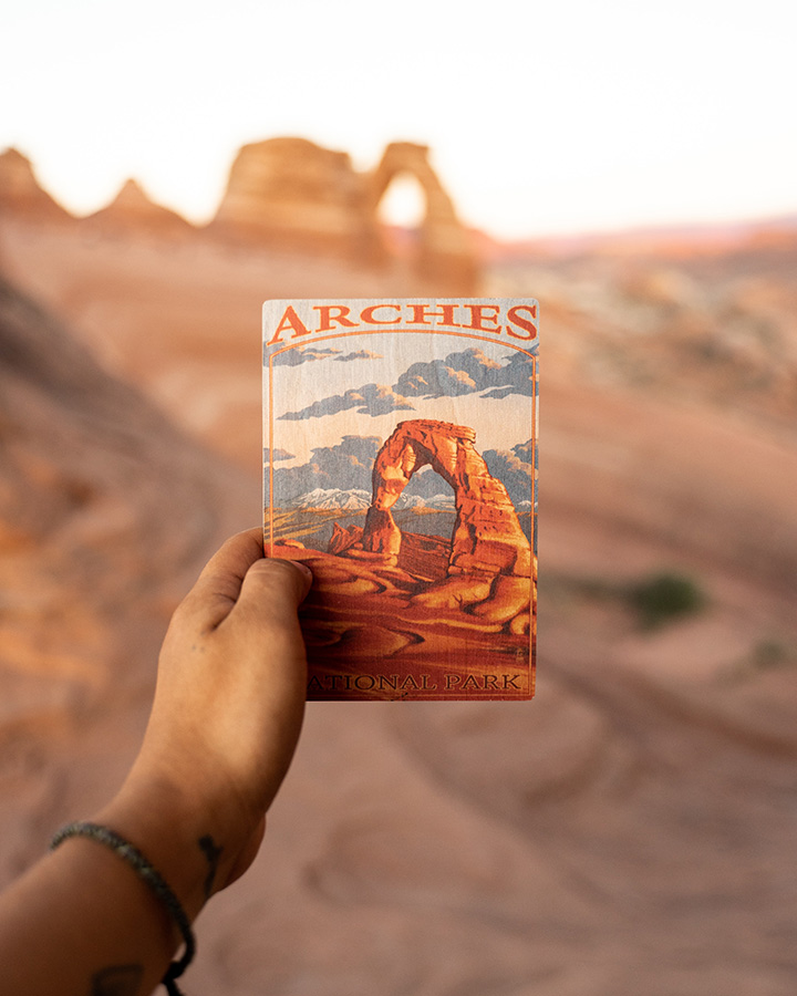 The 31 Best National Park Books for Every Reader 9 A hand holds up a postcard of Arches National Park in Arches National Park