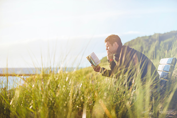 The 31 Best National Park Books for Every Reader 27 A man on a park bench reading a book