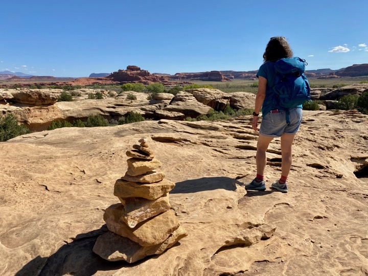 The 15 Best Hikes in Canyonlands National Park: A Comprehensive Guide 40 A woman stands near a cairn marking the trail on a slickrock surface