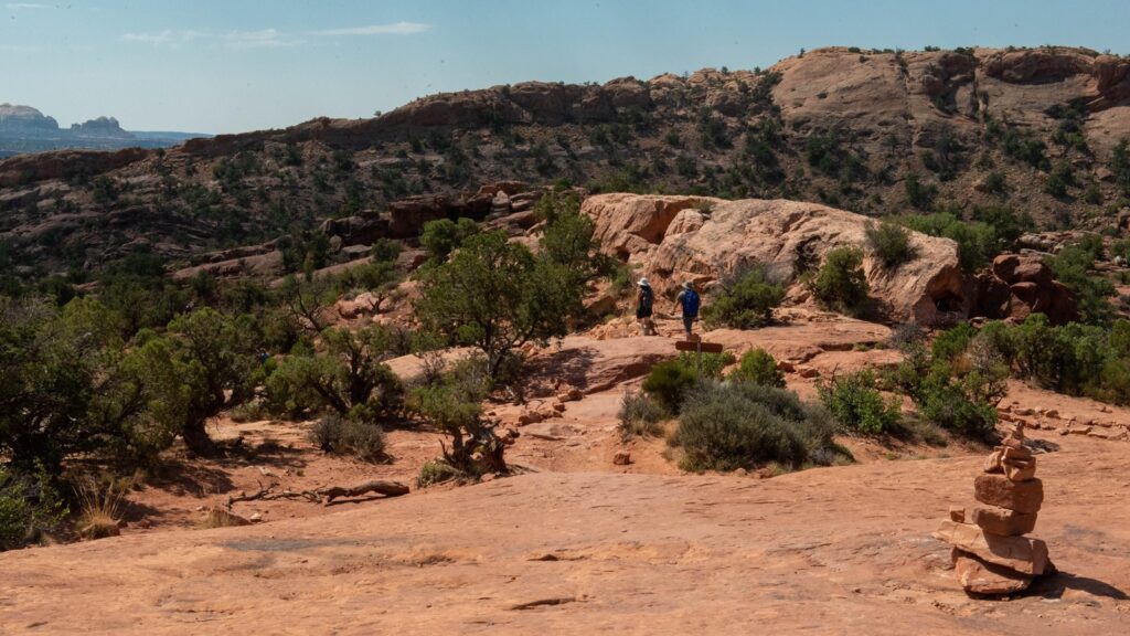 The 15 Best Hikes in Canyonlands National Park: A Comprehensive Guide 37 Hikers on a sandstone rock following cairns