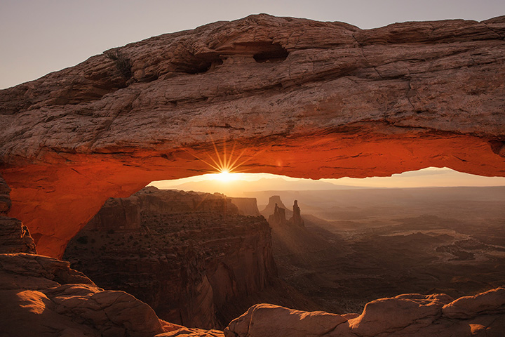 The 15 Best Hikes in Canyonlands National Park: A Comprehensive Guide 26 An arch frames the canyon and mountains beyond at sunrise