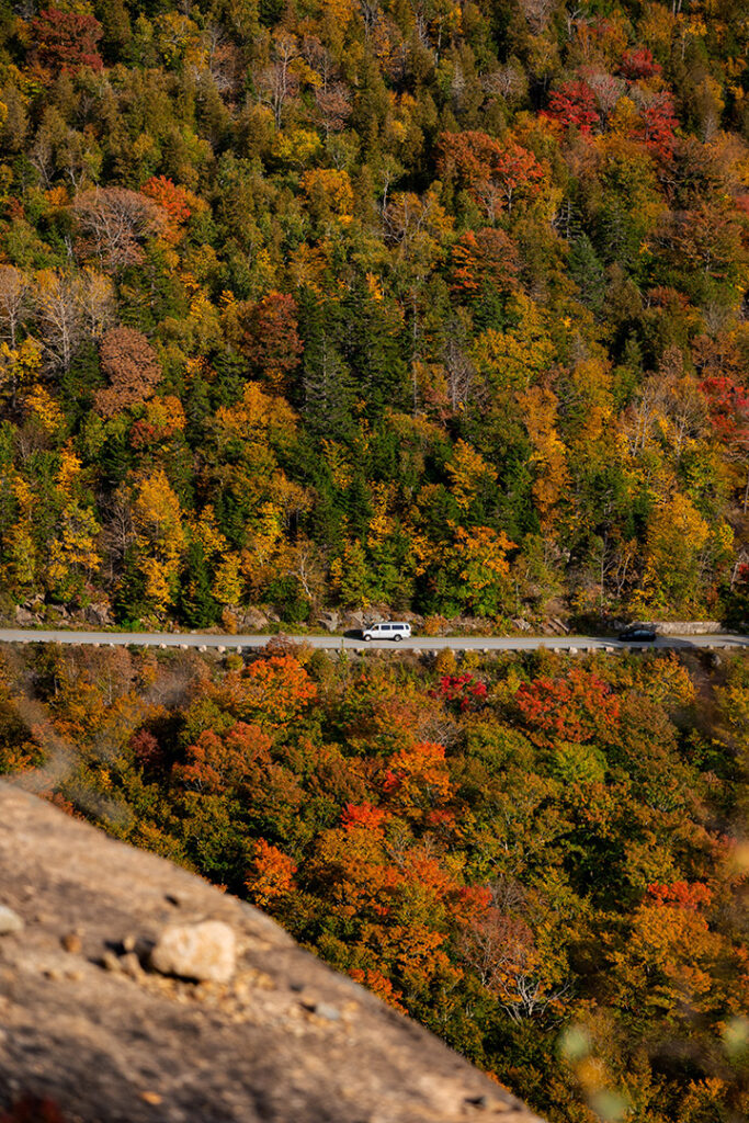 The Best Time to Visit Acadia National Park: When to See Fall Colors 14 A car drives a highway surrounded by fall colors. Fall is the best time to visit Acadia National Park.