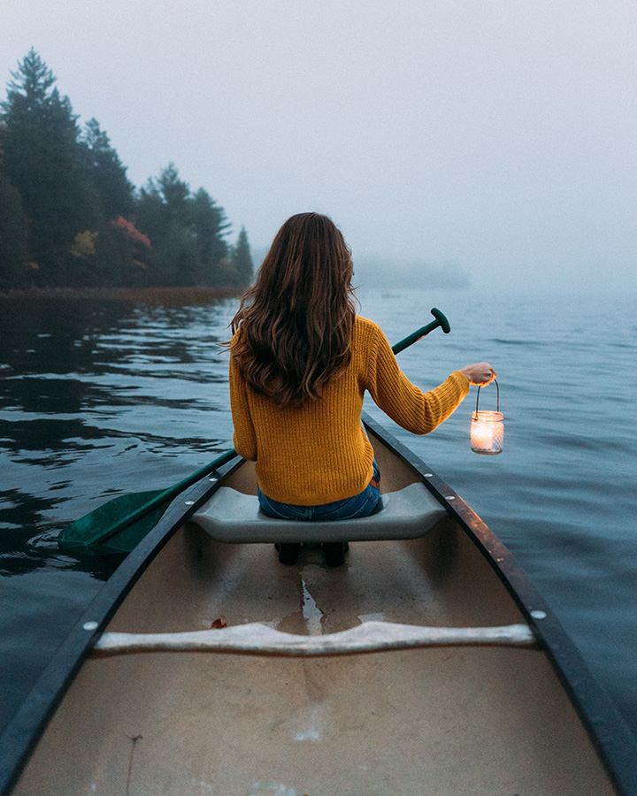 The Best Time to Visit Acadia National Park: When to See Fall Colors 55 A woman in a canoe holding a lantern