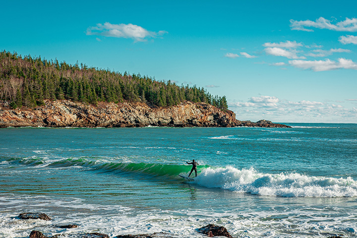 The Best Time to Visit Acadia National Park: When to See Fall Colors 10 A surfer comes in with the waves