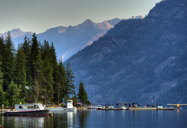 15 Wonderful National Parks in Washington 7 A lake with large mountains reflected in the water. A small boat dock is on the lake shore.