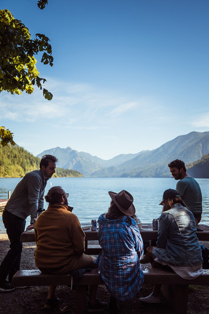 Olympic National Park Camping Guide: Everything You Need to Know About All 15 Olympic National Park Campgrounds 23 A group of 4 campers sit and chat at a picnic table by a lake
