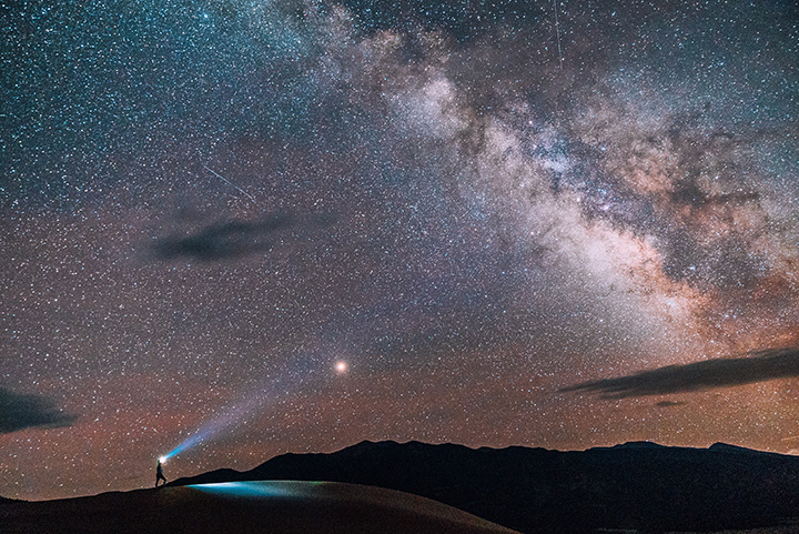 Great Sand Dunes Itinerary: One Day in Great Sand Dunes National Park 32 A hiker on a dunefield with a headlamp at night under the milky way