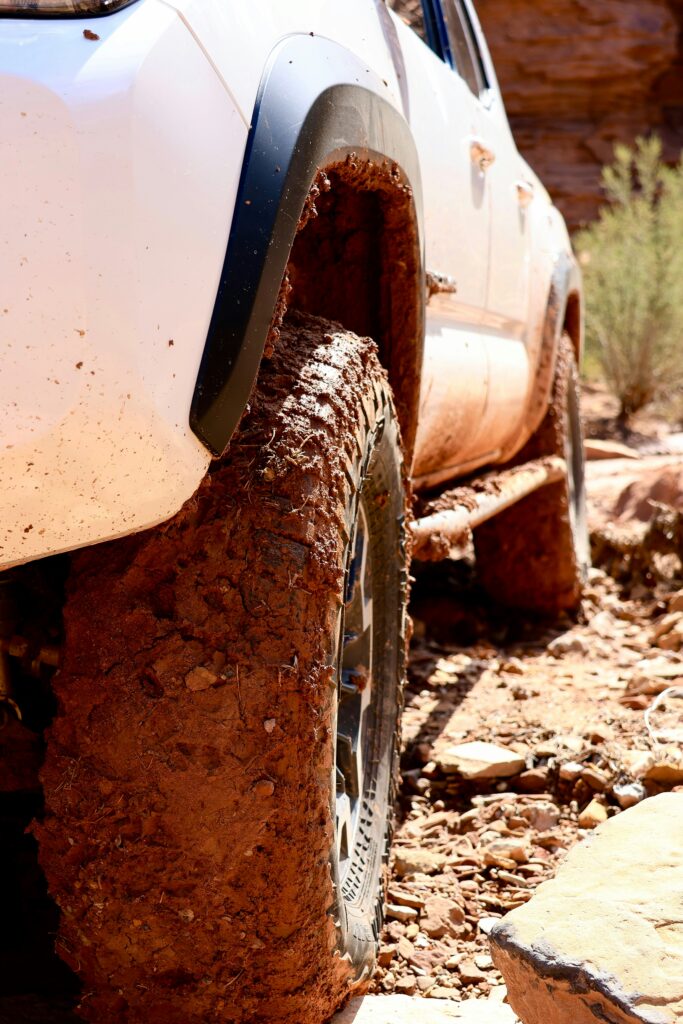 20 Best Hikes in Capitol Reef National Park 3 Tires on a white truck covered in orange mud