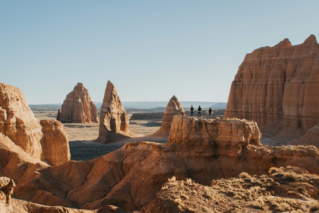 20 Best Hikes in Capitol Reef National Park 4 Three hikers traverse a slim ridge toward towering rock monoliths. This is clearly one of the best hikes in Capitol Reef National Park.