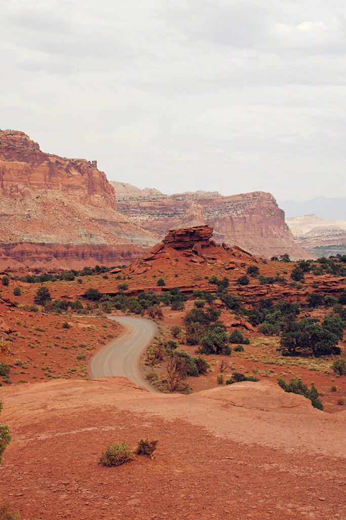 20 Best Hikes in Capitol Reef National Park 12 A paved road winds through scenic orange geologic formations on a cloudy day